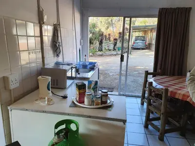 a kitchen with a counter and a table and a window at Kaapsche Draai in Kaapsehoop
