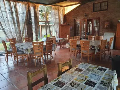 a dining room with tables and chairs and a brick wall at Kaapsche Draai in Kaapsehoop