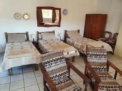 a room with three beds and a mirror and chairs at Kaapsche Draai in Kaapsehoop