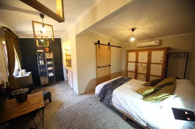 a bedroom with a bed and a table in it at SOUSIE'S RUSTIC STAY in Polokwane