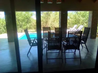 a dining table and chairs in a room with a pool at Lionsview Private Lodge - 4 Lions in Marloth Park