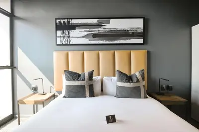 a bedroom with a large white bed with a large headboard at The Capital Mbombela in Nelspruit