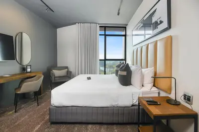 a hotel room with a large bed and a desk and a desk at The Capital Mbombela in Nelspruit