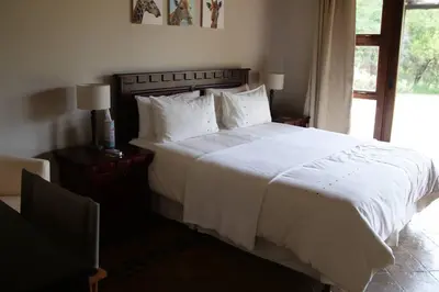a bedroom with a large white bed with a window at 86 Zebula 10 Sleeper Lodge in Mabula