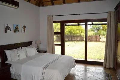 a bedroom with a large bed and a large window at 86 Zebula 10 Sleeper Lodge in Mabula