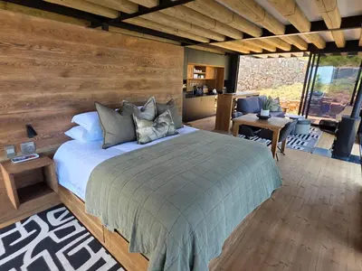 a bedroom with a large bed and a living room at Eagle View on Beumont in Dullstroom