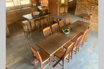 a kitchen with a wooden table with chairs and a tableasteryasteryasteryasteryastery at Thala Thala Private Villa in the bush-veld in Cullinan