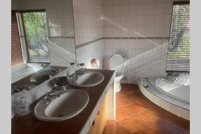 a bathroom with two sinks and a tub and a toilet at Thala Thala Private Villa in the bush-veld in Cullinan
