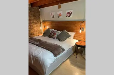 a bedroom with a white bed with a brick wall at Thala Thala Private Villa in the bush-veld in Cullinan