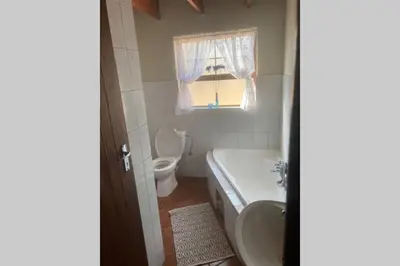 a bathroom with a sink and a toilet and a window at Thala Thala Private Villa in the bush-veld in Cullinan