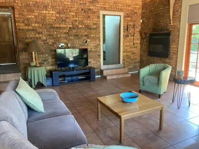 a living room with a couch and a table and a tv at Thala Thala Private Villa in the bush-veld in Cullinan