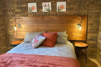 a bed with a wooden headboard and pillows on it at Thala Thala Private Villa in the bush-veld in Cullinan