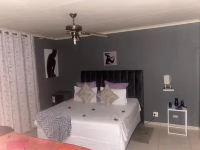 a bedroom with a white bed with purple walls at Warmbaths Thai Spa and Guest House in Bela-Bela