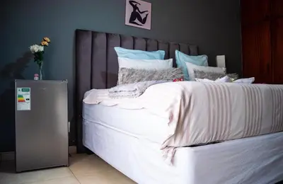 a bedroom with a large bed with white sheets and pillows at Warmbaths Thai Spa and Guest House in Bela-Bela