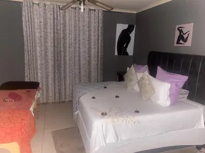 a bedroom with a bed with white sheets and purple pillows at Warmbaths Thai Spa and Guest House in Bela-Bela