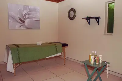 a room with a bed and a table and a clock at Warmbaths Thai Spa and Guest House in Bela-Bela