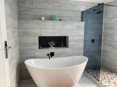 a white bath tub in a bathroom with a fireplace at The King's Court Guest Manor in Bela-Bela