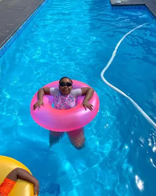 a woman in a swimming pool with a pink raft at The King's Court Guest Manor in Bela-Bela