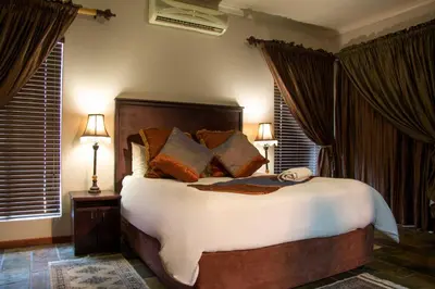a bedroom with a large bed with brown curtains at Zoete Rust Boutique Hotel in Lephalale