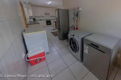 a kitchen with a washing machine and a refrigerator at Mamba Bush House in Marloth Park