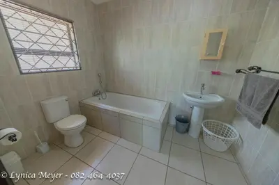 a bathroom with a tub and a toilet and a sink at Mamba Bush House in Marloth Park