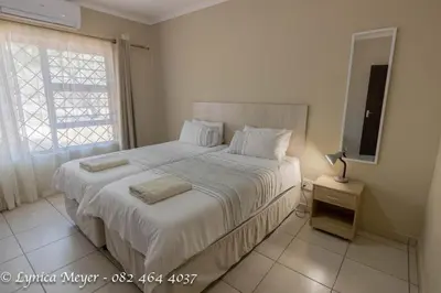 a bedroom with a large white bed with a window at Mamba Bush House in Marloth Park