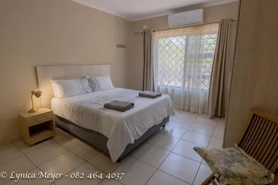 a bedroom with a large bed and a window at Mamba Bush House in Marloth Park