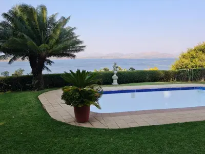 a swimming pool in a yard with a palm tree at Kosmos View Luxury Apartments in Hartbeespoort