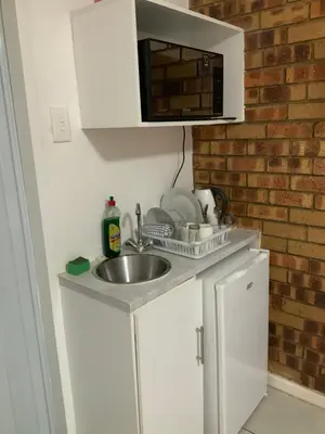 a small kitchen with a sink and a microwave at GTI Guest House in Pretoria