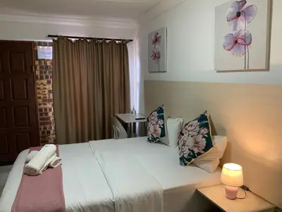 a bedroom with a bed with a lamp and a window at GTI Guest House in Pretoria