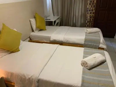two beds in a hotel room with a towel on it at GTI Guest House in Pretoria