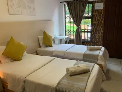 two beds in a room with a window at GTI Guest House in Pretoria