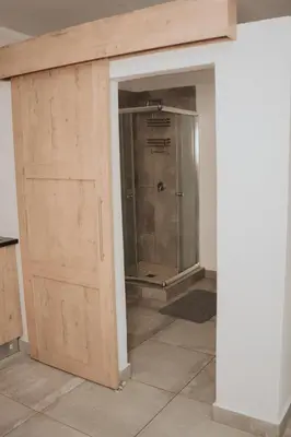 a bathroom with a shower and a wooden door at Pretorius Park in Hartbeespoort