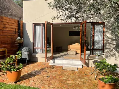a house with a patio with a bed in the background at Olive Branch Cottage off grid in Benoni