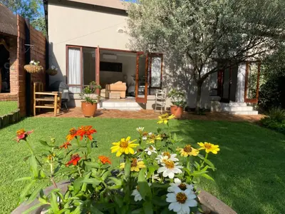a garden with flowers in front of a house at Olive Branch Cottage off grid in Benoni