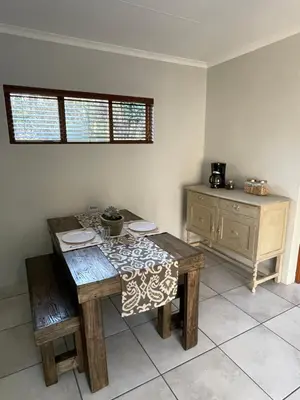 a dining room with a table and chairs and a cabinet at Olive Branch Cottage off grid in Benoni