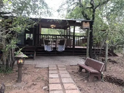 a wooden pergola with a bench and a table and a bench at Pheasant's Crest in Marloth Park