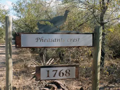 a sign for a pheasants crest with a bird on it at Pheasant's Crest in Marloth Park