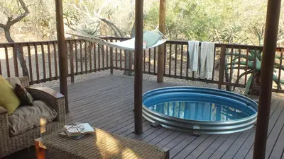 a hot tub on a deck with a hammock at Pheasant's Crest in Marloth Park