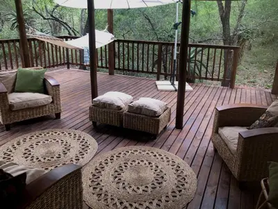 a wooden deck with chairs and tables and an umbrella at Pheasant's Crest in Marloth Park