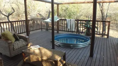 a deck with a hot tub and a hammock at Pheasant's Crest in Marloth Park