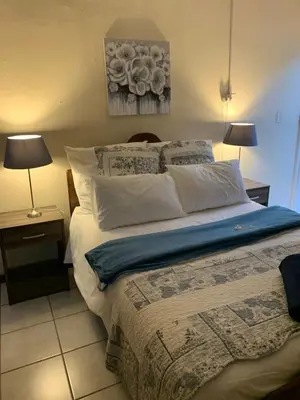 a bedroom with a bed with two lamps and a painting at Cottage 32 in Groblersdal
