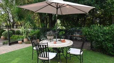 a table and chairs with an umbrella in a yard at LUXURY ROOM @ 4 STAR GUEST HOUSE in Middelburg