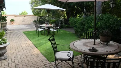 a patio with tables and chairs and an umbrella at LUXURY ROOM @ 4 STAR GUEST HOUSE in Middelburg