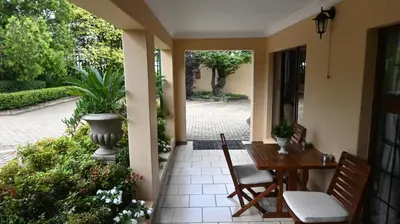 a porch with a table and chairs and a courtyard at LUXURY ROOM @ 4 STAR GUEST HOUSE in Middelburg
