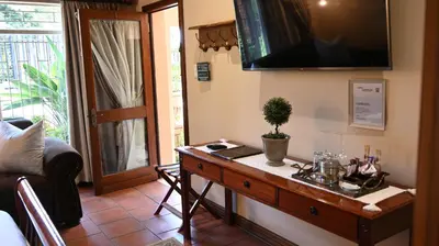 a living room with a table with a tv on the wall at LUXURY ROOM @ 4 STAR GUEST HOUSE in Middelburg