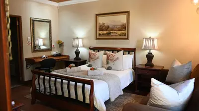 a bedroom with a bed and a desk and a mirror at LUXURY ROOM @ 4 STAR GUEST HOUSE in Middelburg