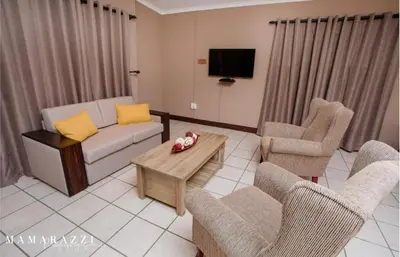 a living room with a couch and chairs and a tv at 4 Gazelle Guesthouse in Nelspruit