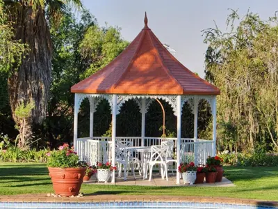a gazebo with a table and chairs in a yard at Villa Sardinia Guest House in Midrand