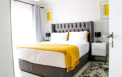 a bedroom with a large bed with a yellow blanket on it at Twelve Eighty at The Blyde Crystal Lagoon in Pretoria
